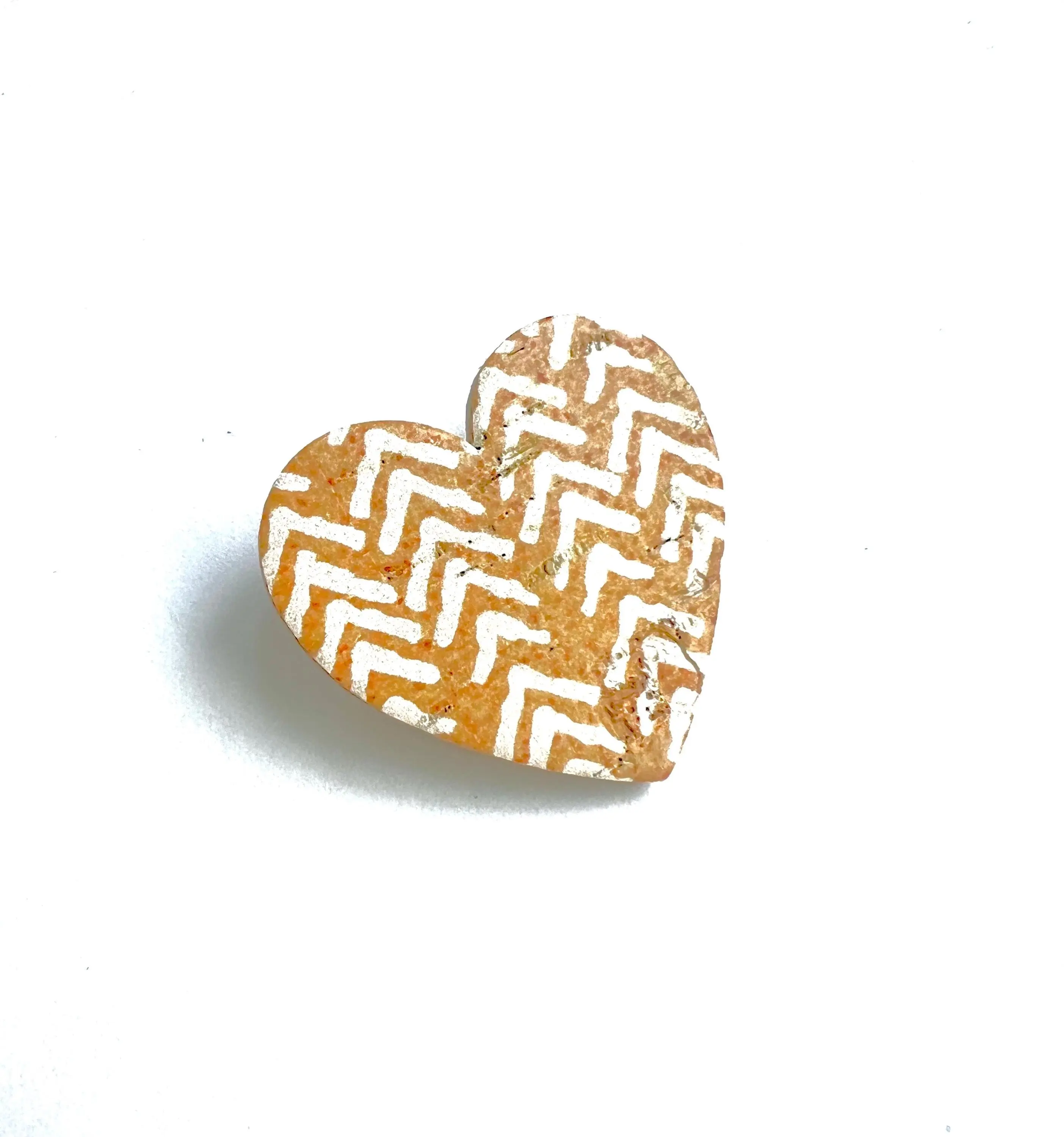 Heart brooch in cork and leather with a chevron pattern on a mustard yellow background