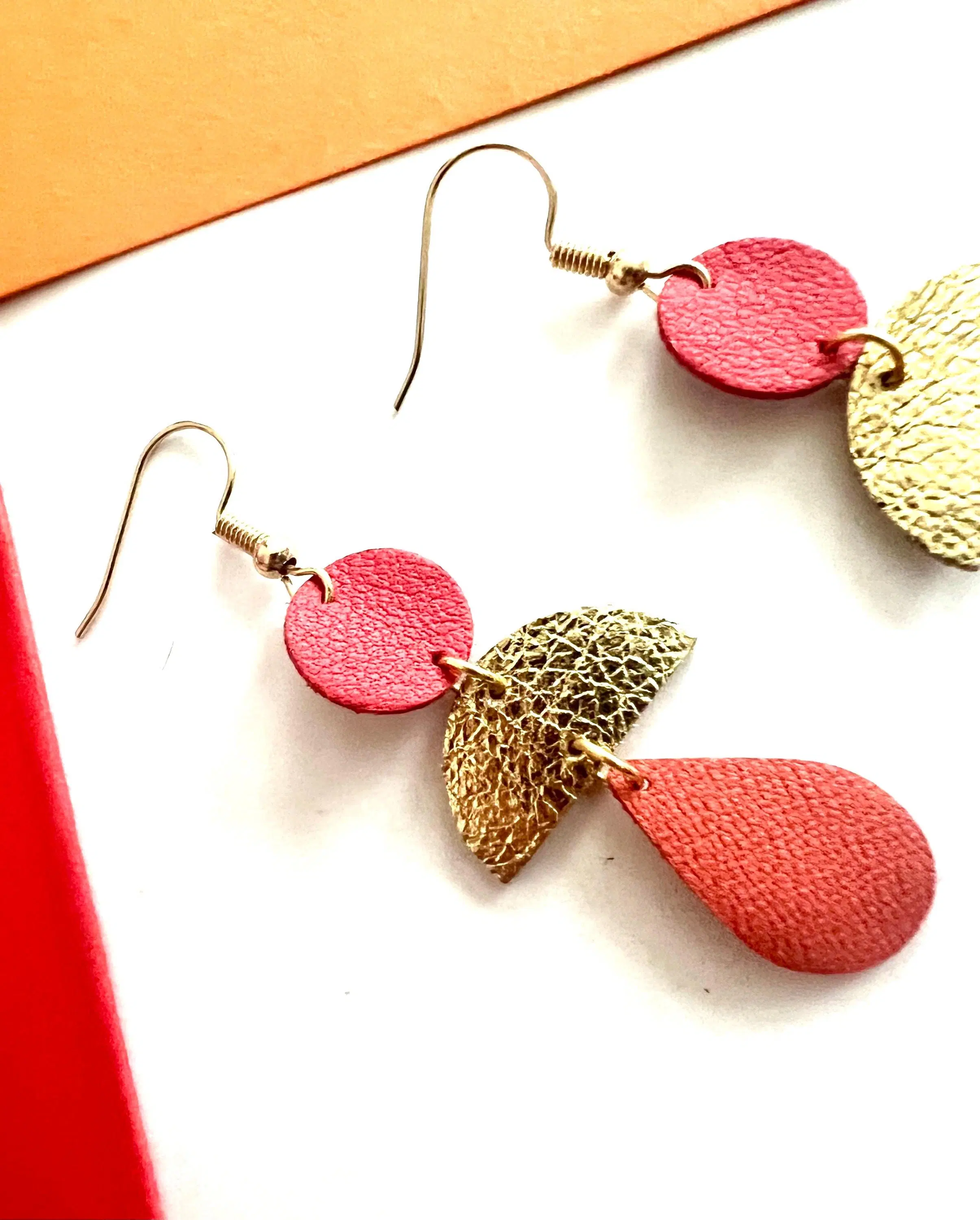 JOA model leather earrings in red, gold, and coral